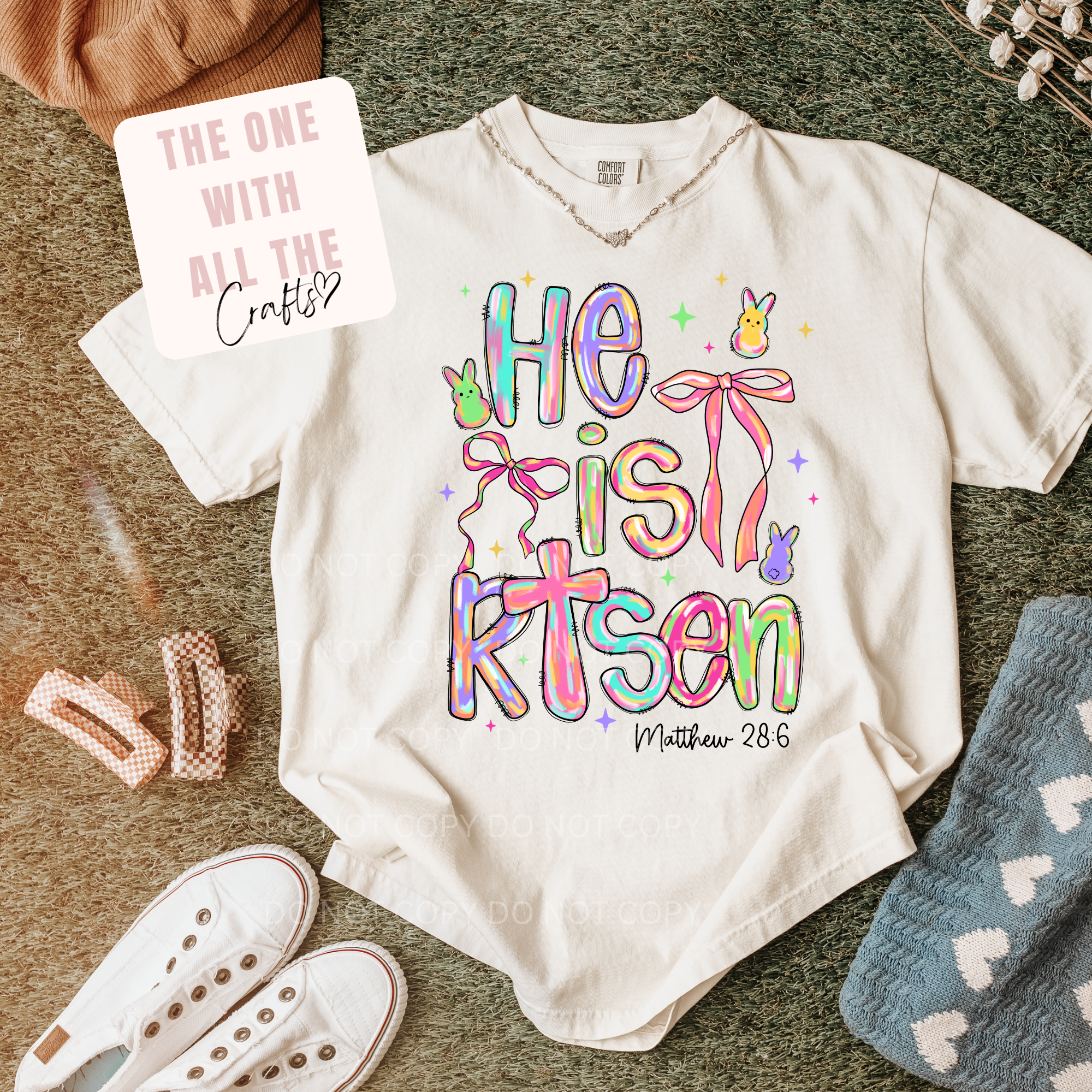White t-shirt with colorful text design on a textured surface with accessories.