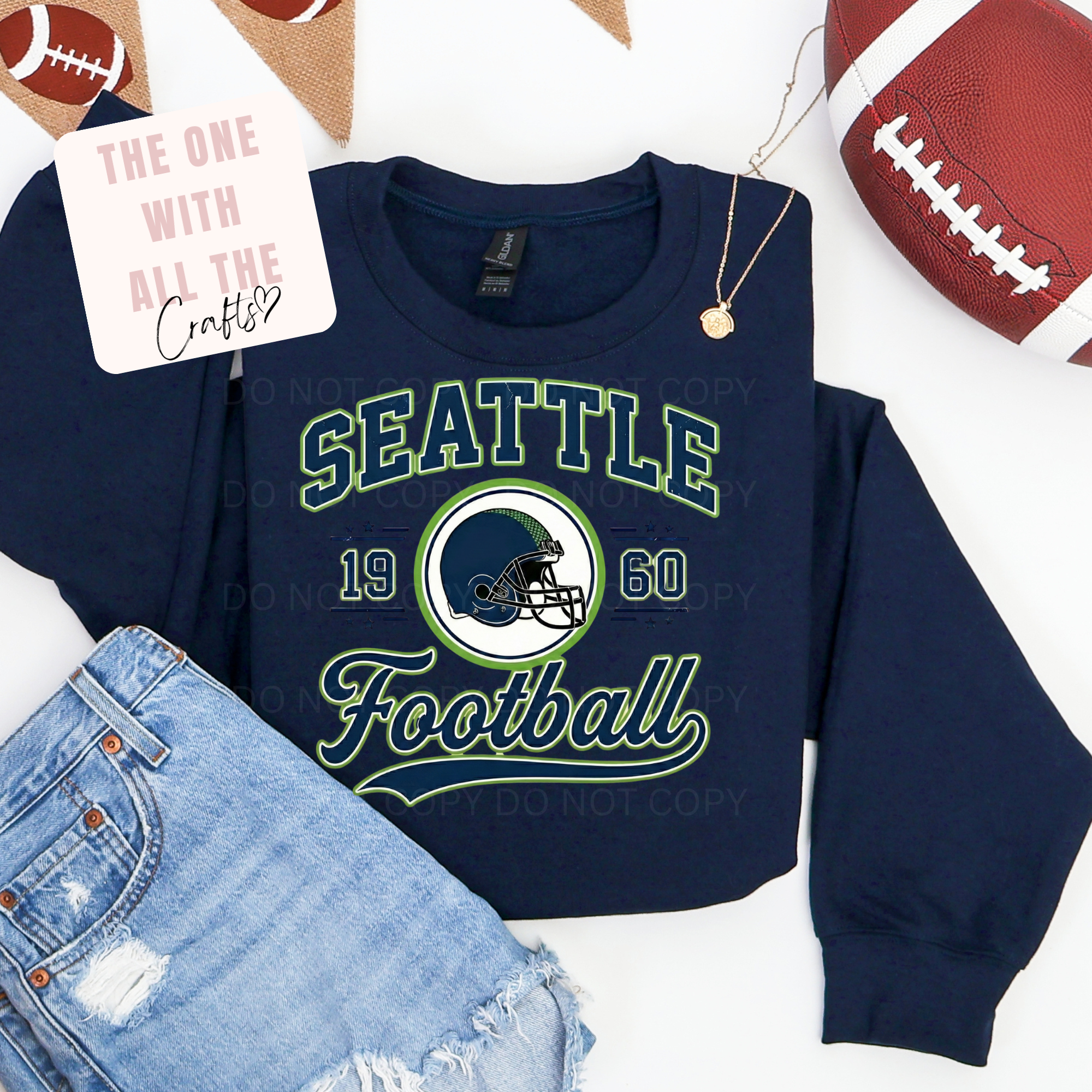 Navy blue sweatshirt with 'Seattle Football' text and helmet graphic, displayed with jeans and footballs.