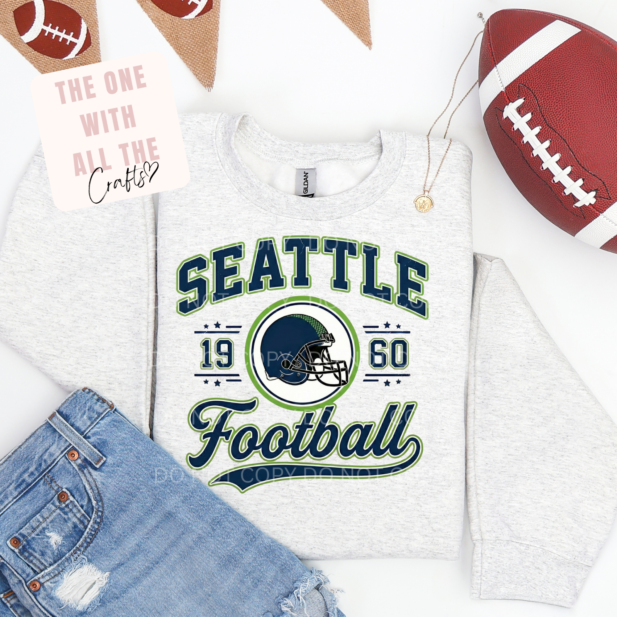 White t-shirt with 'Seattle Football' design, football and jeans on a white background