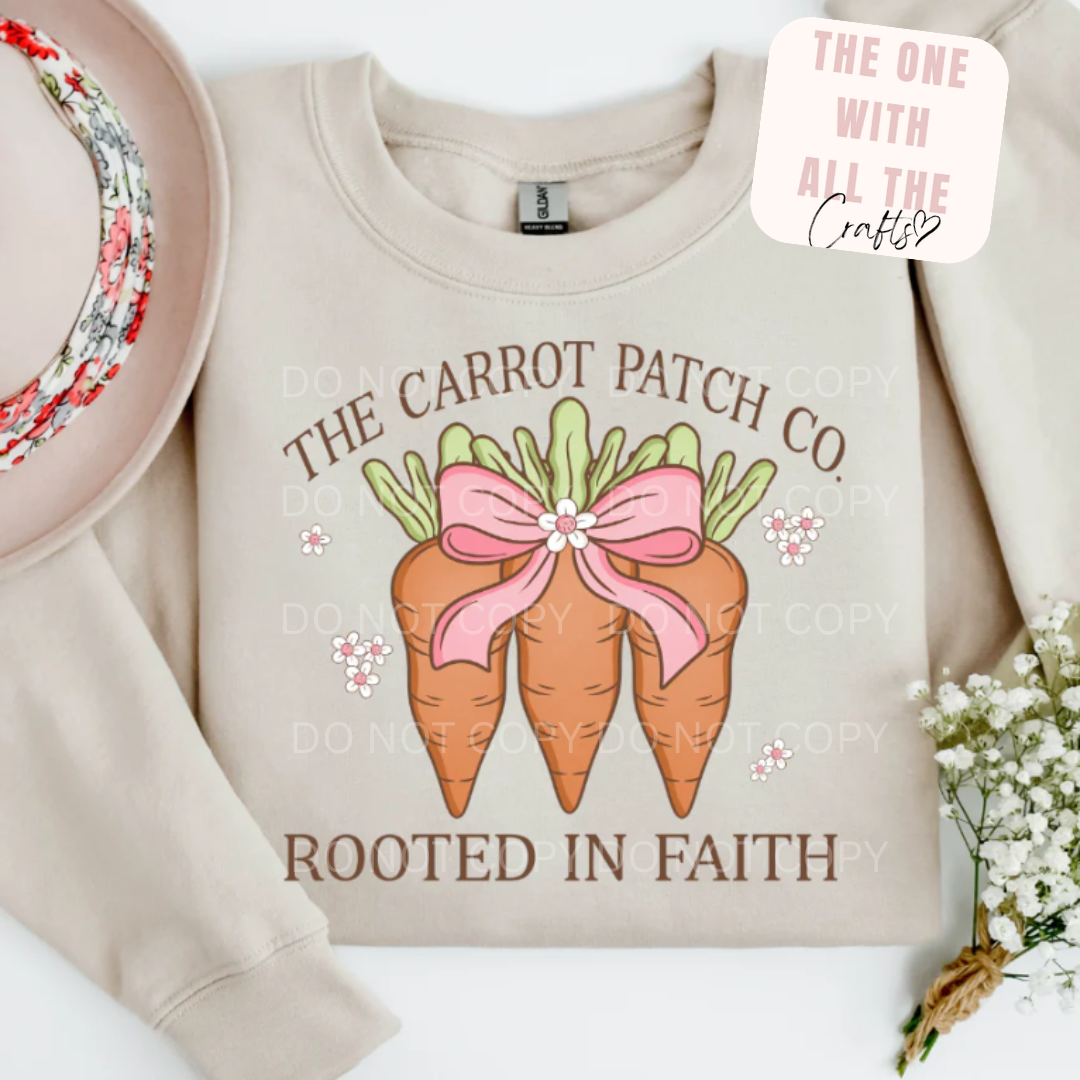 Beige sweatshirt with 'The Carrot Patch Co' and 'Rooted in Faith' text, featuring cartoon carrots with a pink bow.