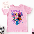 Pink t-shirt with cartoon characters and 'HUNTRAX' text on a white background