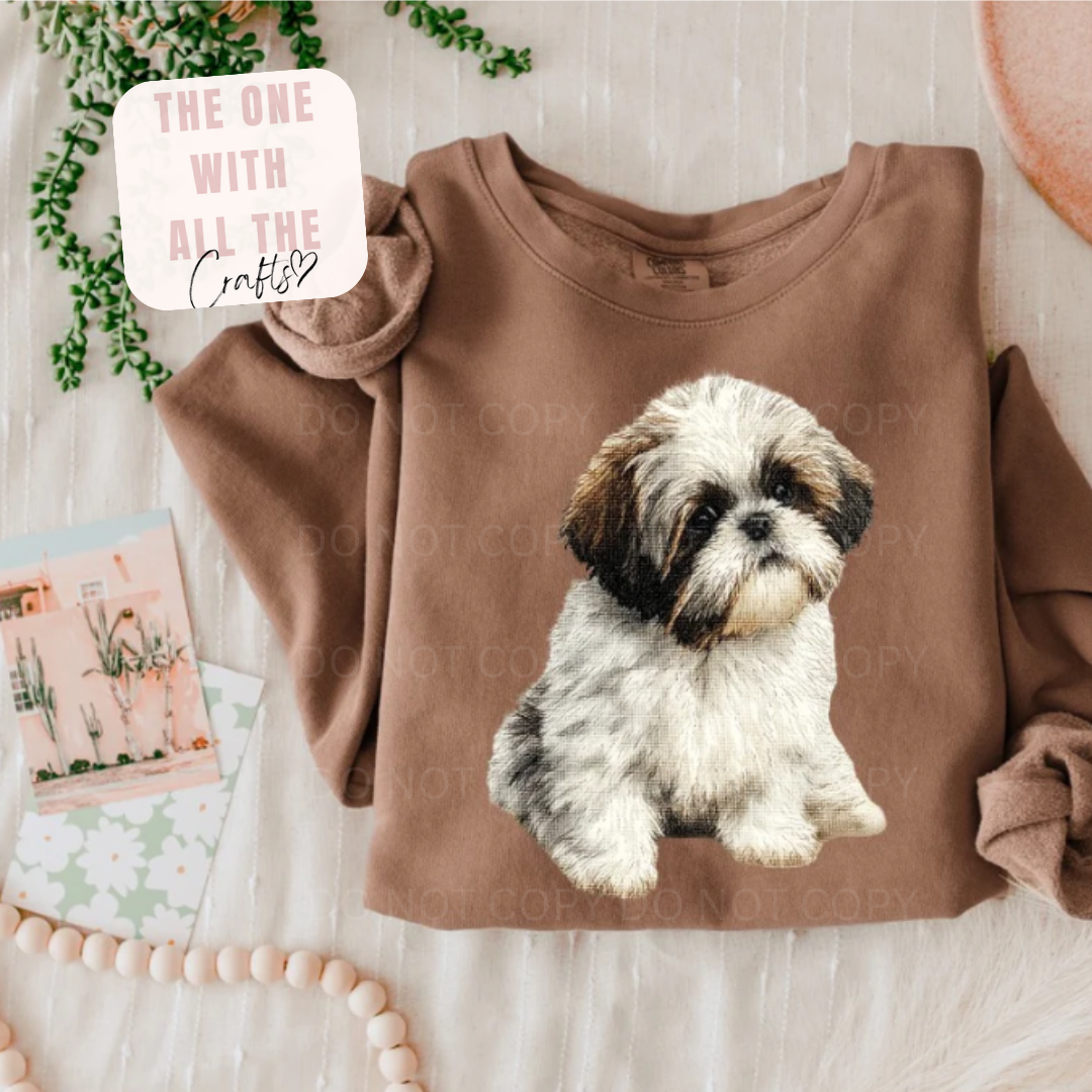 Brown sweatshirt with a dog graphic on a light wooden surface.