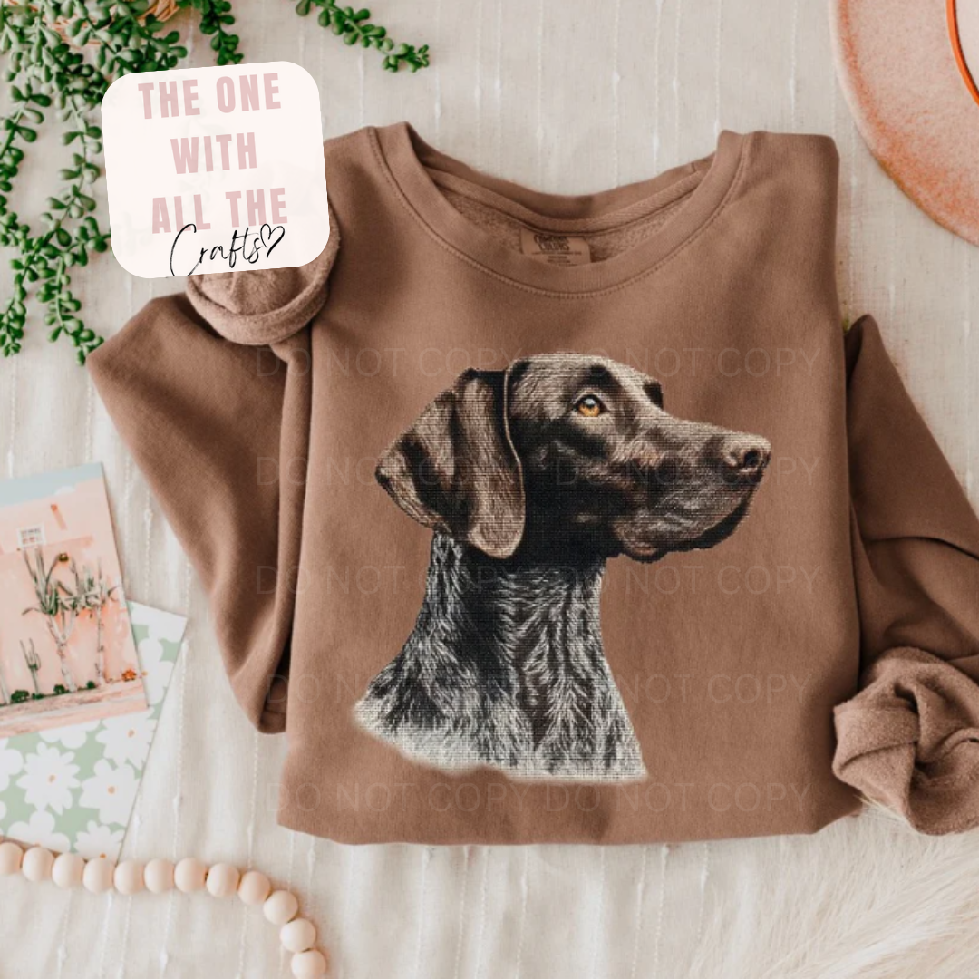 Brown sweatshirt with a dog graphic on a light wooden surface
