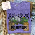 Purple t-shirt with farm-themed design featuring a tractor, boots, and grain sack on a textured surface.