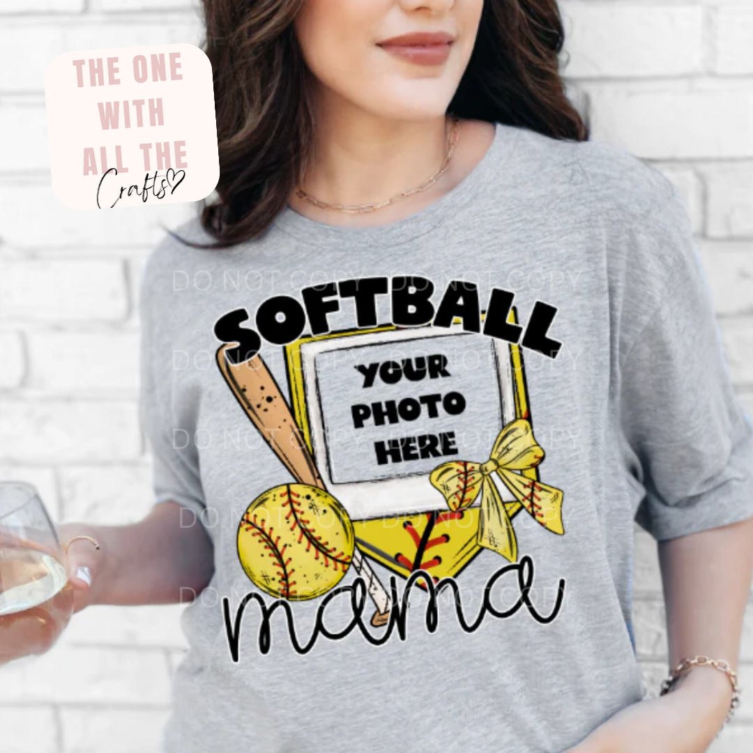 Gray t-shirt with 'SOFTBALL MAMA' design worn by a person, against a white brick wall.