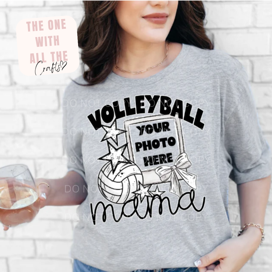Person wearing a gray t-shirt with 'Volleyball Your Photo Here Mama' design against a white brick wall.