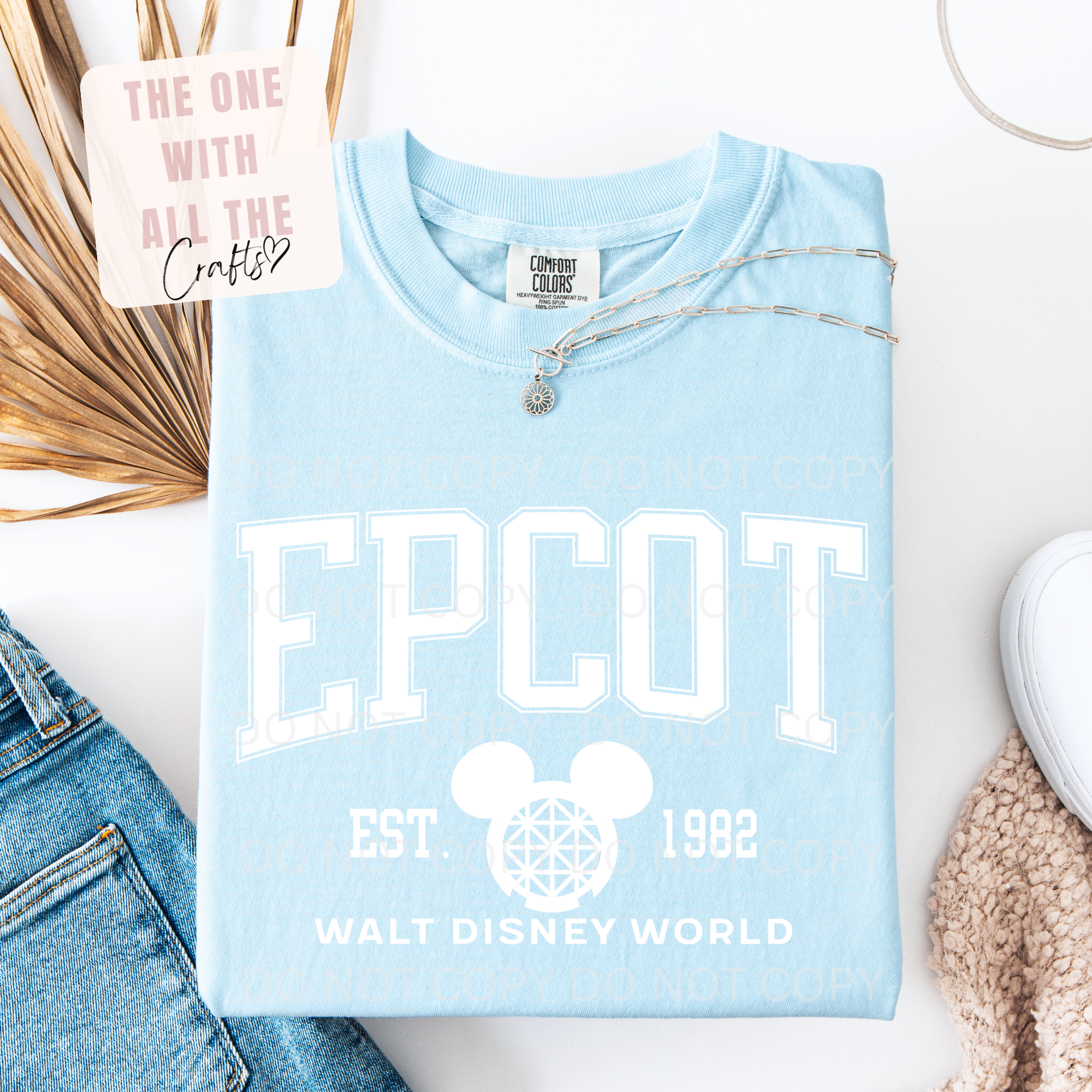 Light blue t-shirt with 'EPCOT' and Disney logo on a white surface with jeans and sneakers.