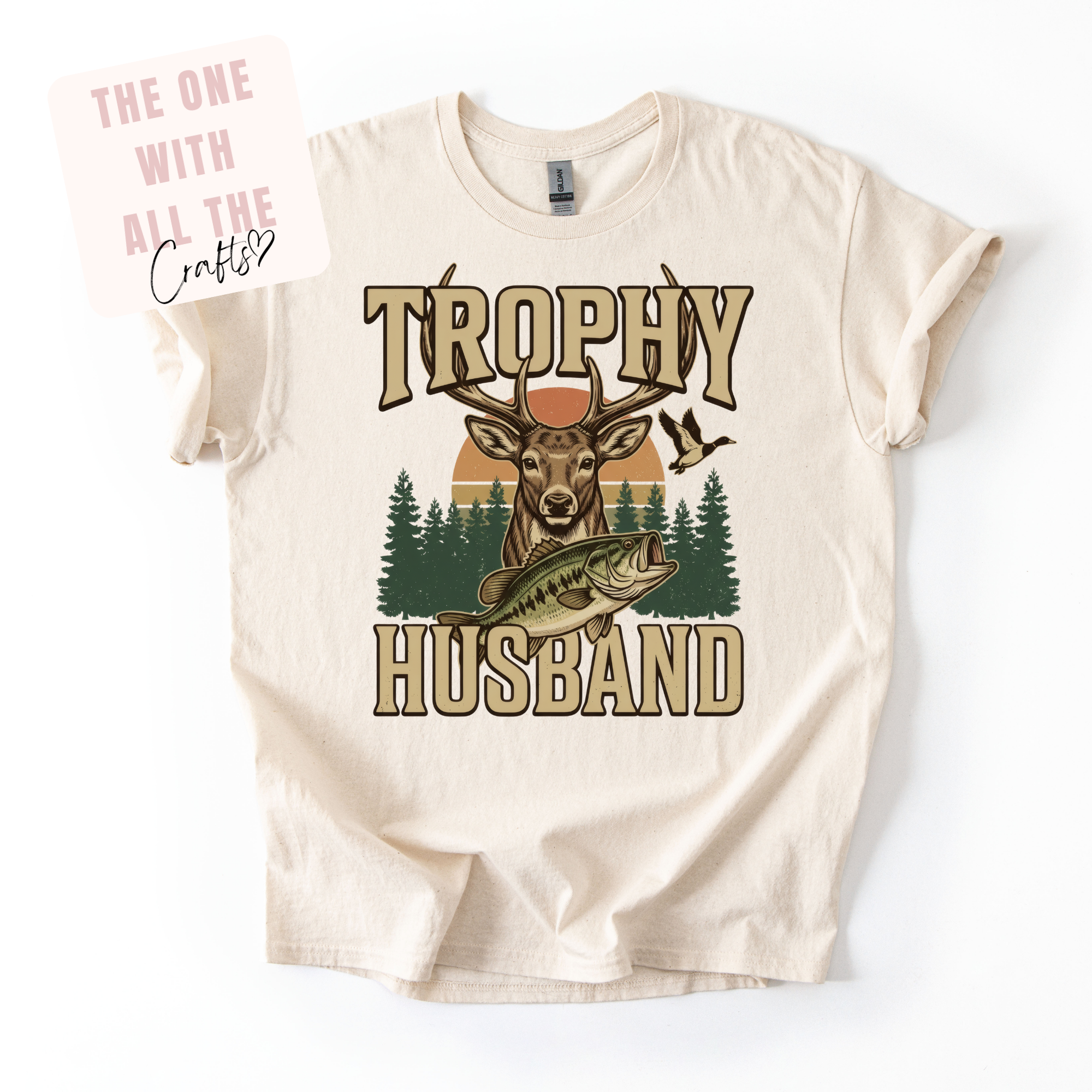 Beige t-shirt with 'Trophy Husband' graphic design featuring a deer and fish, on a white background.