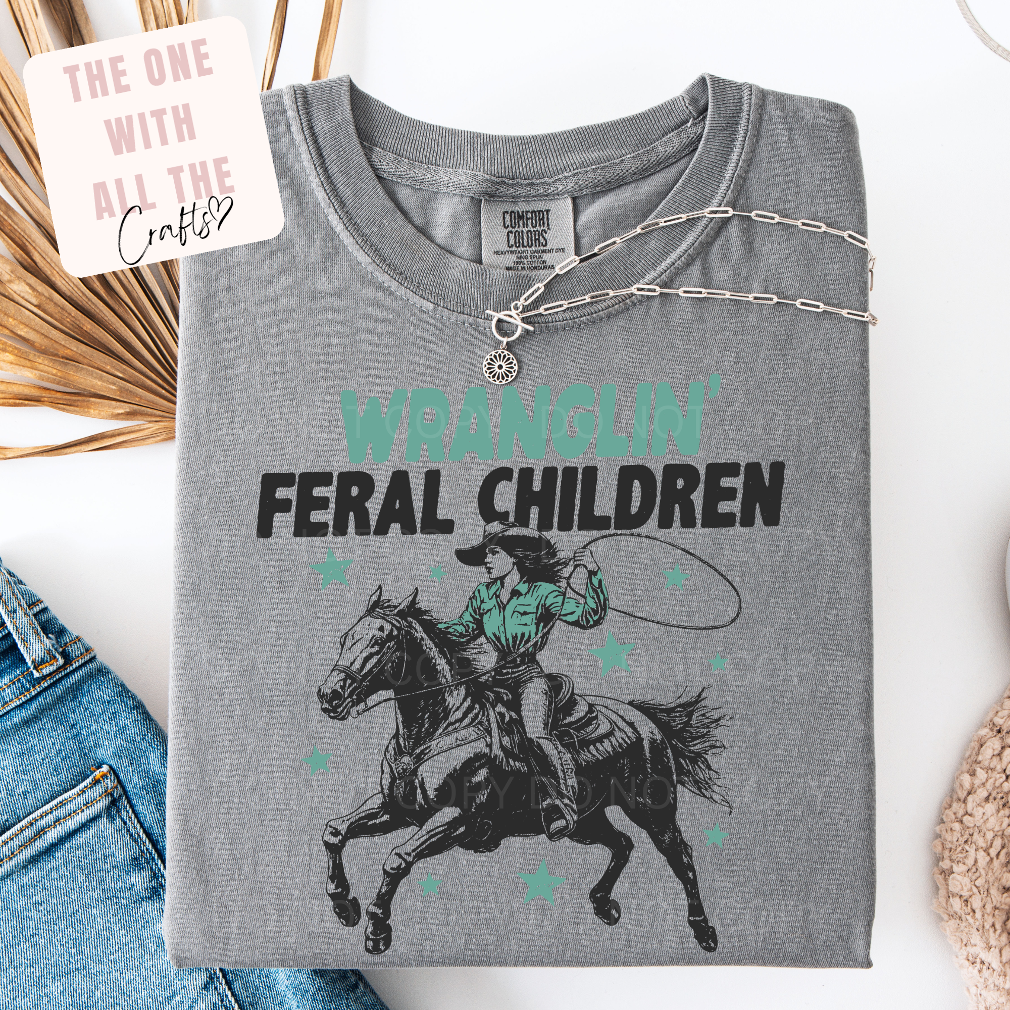 Gray t-shirt with graphic design and text 'Wrangling Feral Children' on a white background
