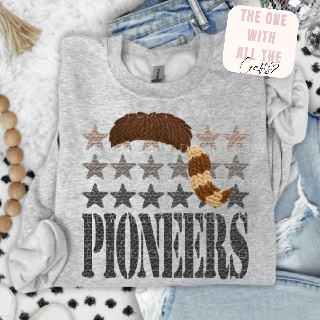 Gray sweatshirt with star pattern and 'Pioneers' text, displayed on a hanger with jeans and decorative items.